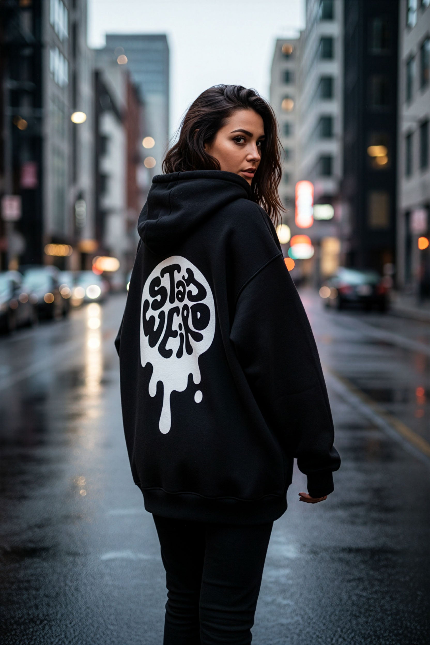 Woman wearing a black hoodie with a logo on the back in an urban setting
