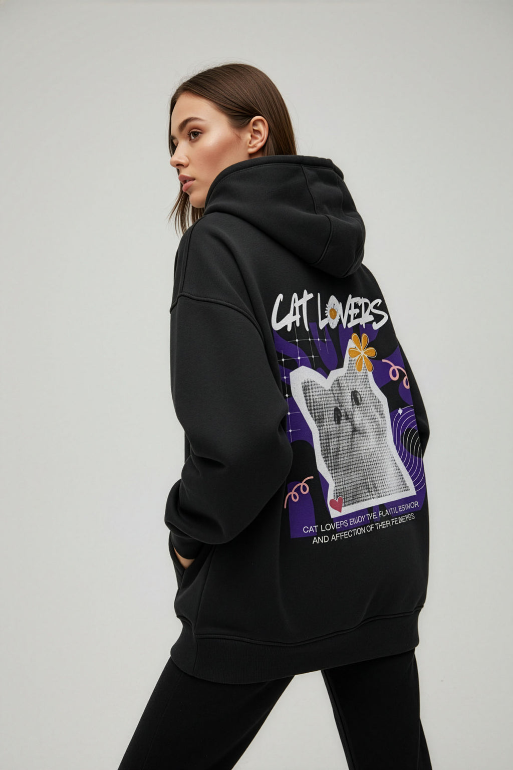 Person wearing a black hoodie with a cat-themed design on the back, on a plain background