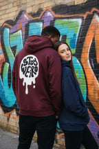Two people wearing hoodies in front of a graffiti-covered wall