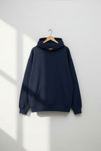 Navy blue hoodie on a wooden hanger against a white wall